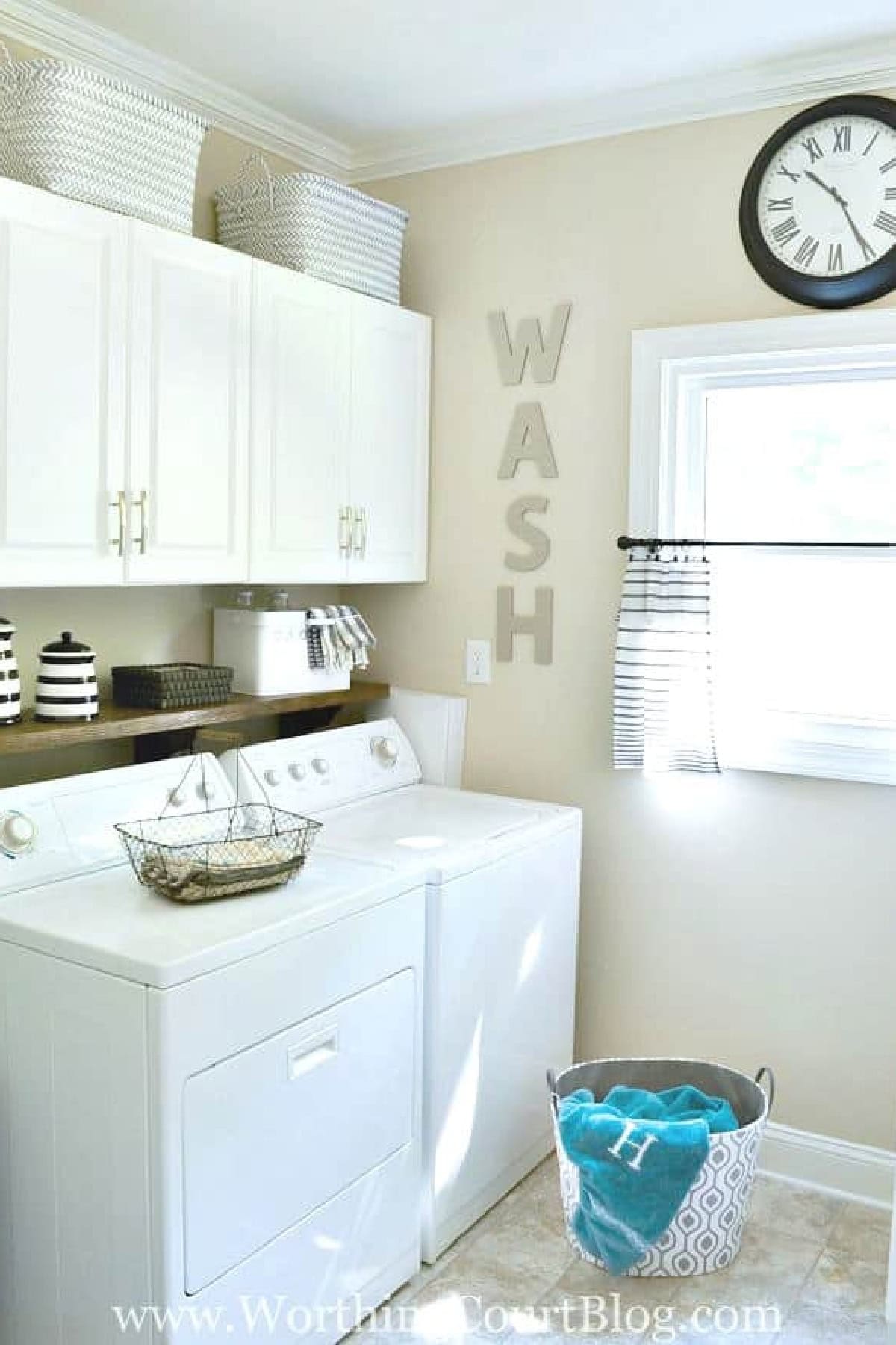 partial view of a laundry room with white washer and dryer with white cabinets above