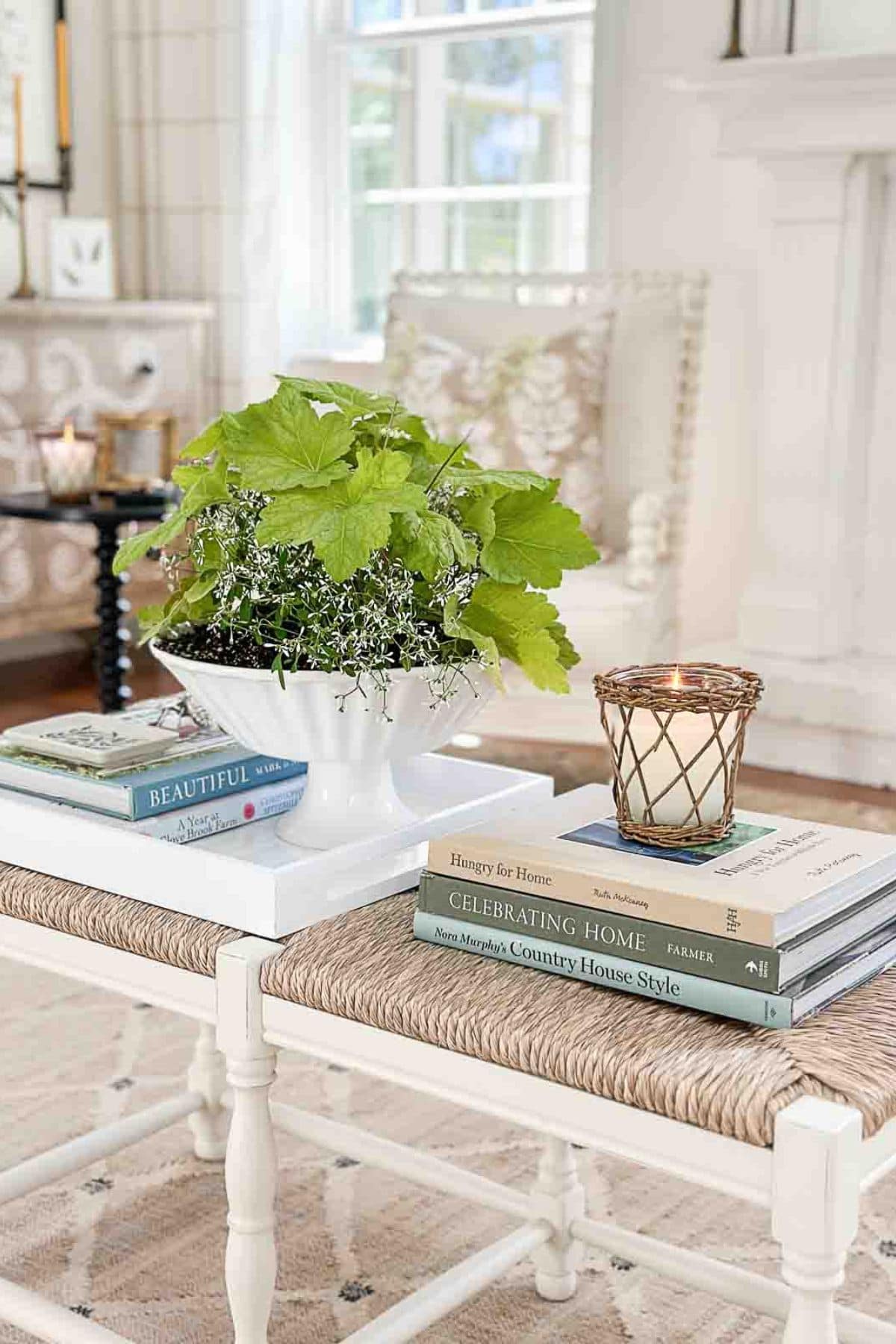 summer vignette with a white pedestal bowl filled with greenery on a coffee table
