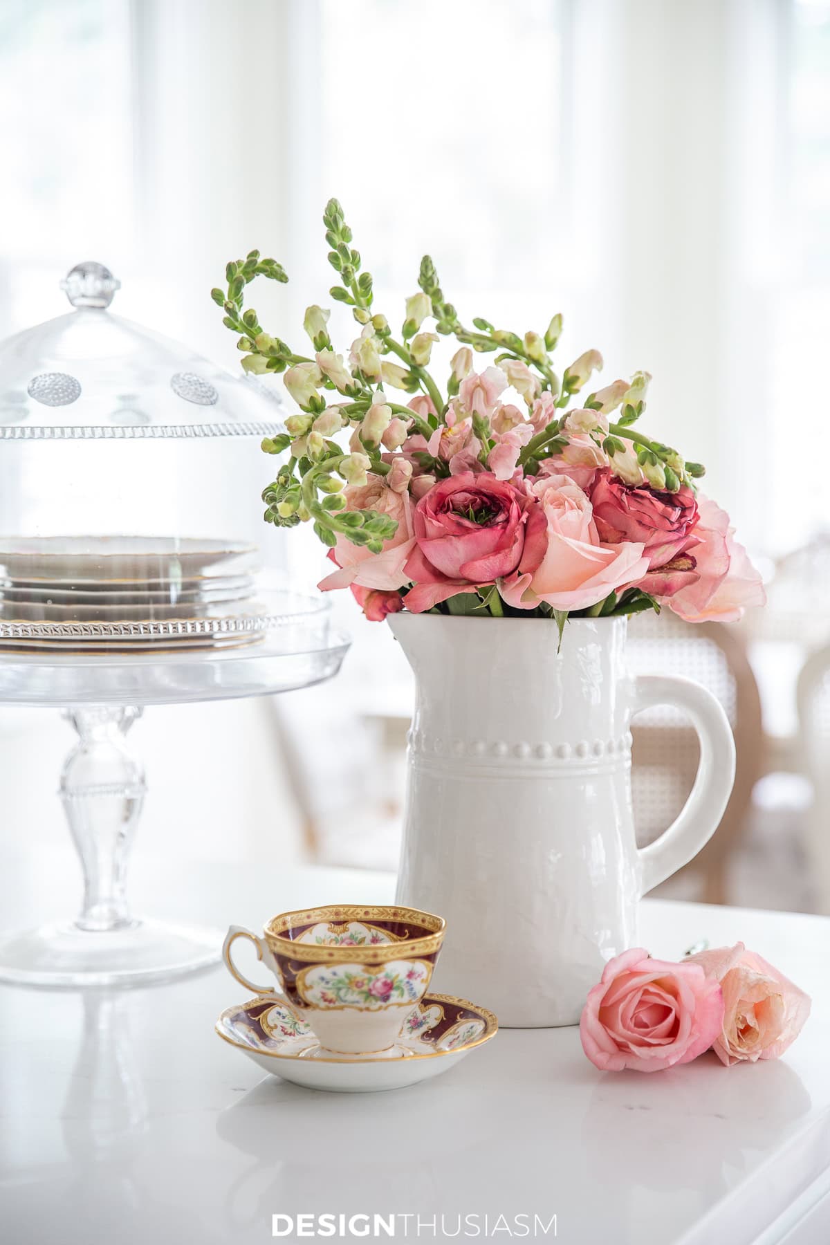 white vase filled with pink summer flowers in a vignette with other dishes