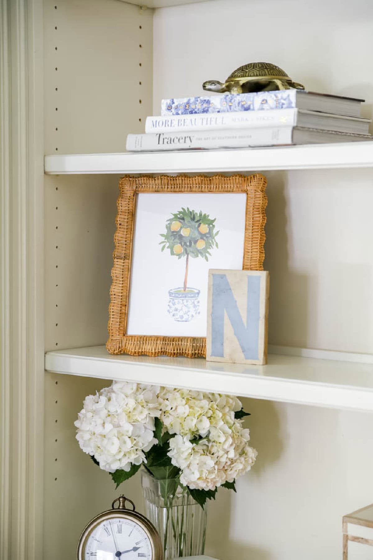 lemon tree topiary print in a rattan frame on a bookcase with other decor