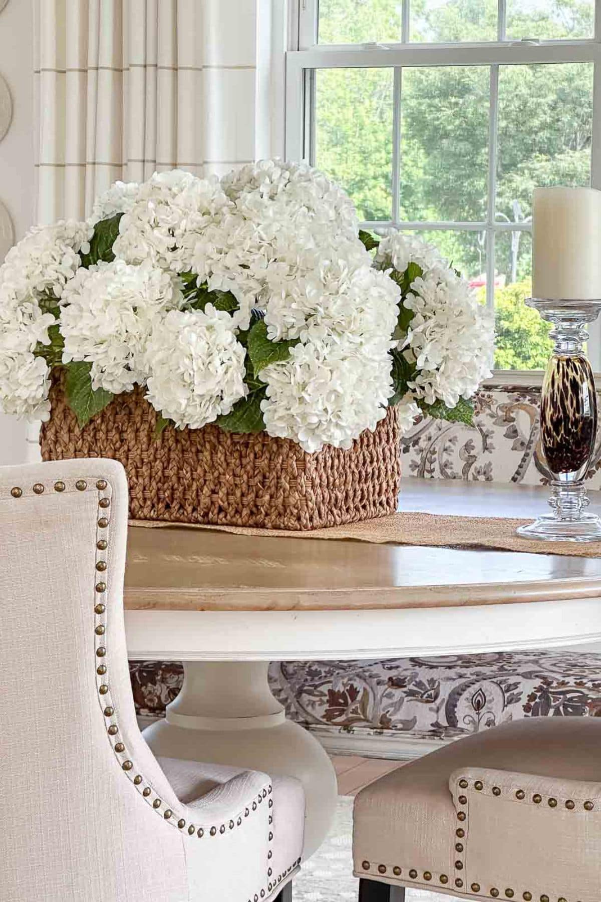 basket of white hydrangeas on a wood table in front of a window