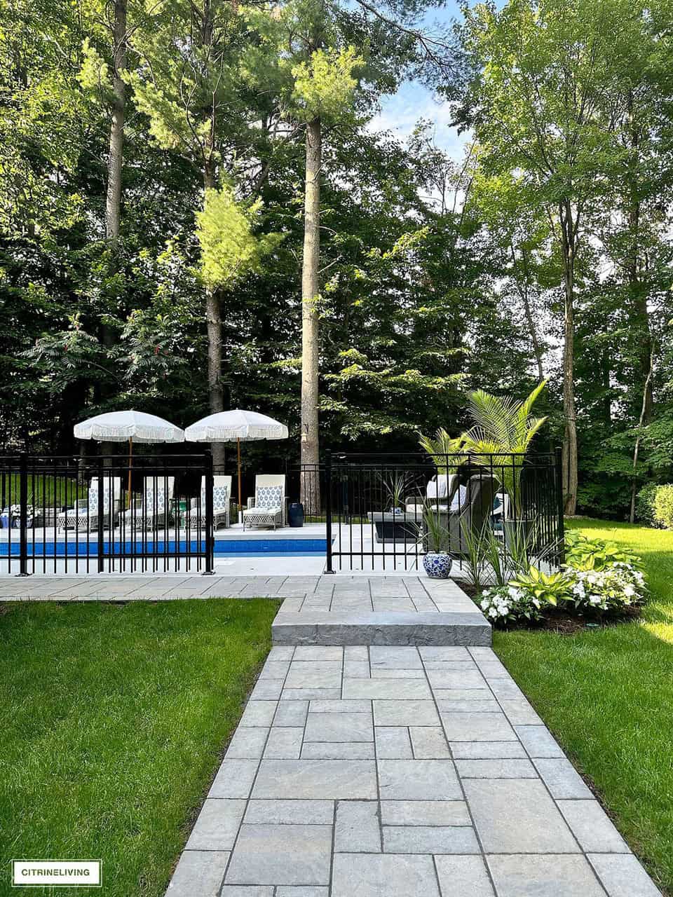 partial view of an in ground swimming pool with a black wrought iron fence