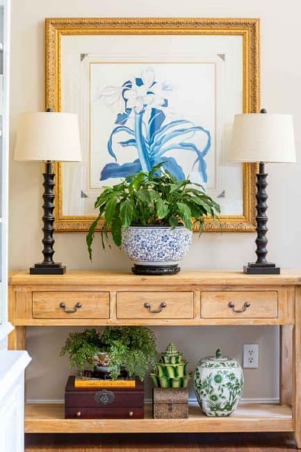 unfinished pine console table with a pair of lamps and a large plant in a blue and white container