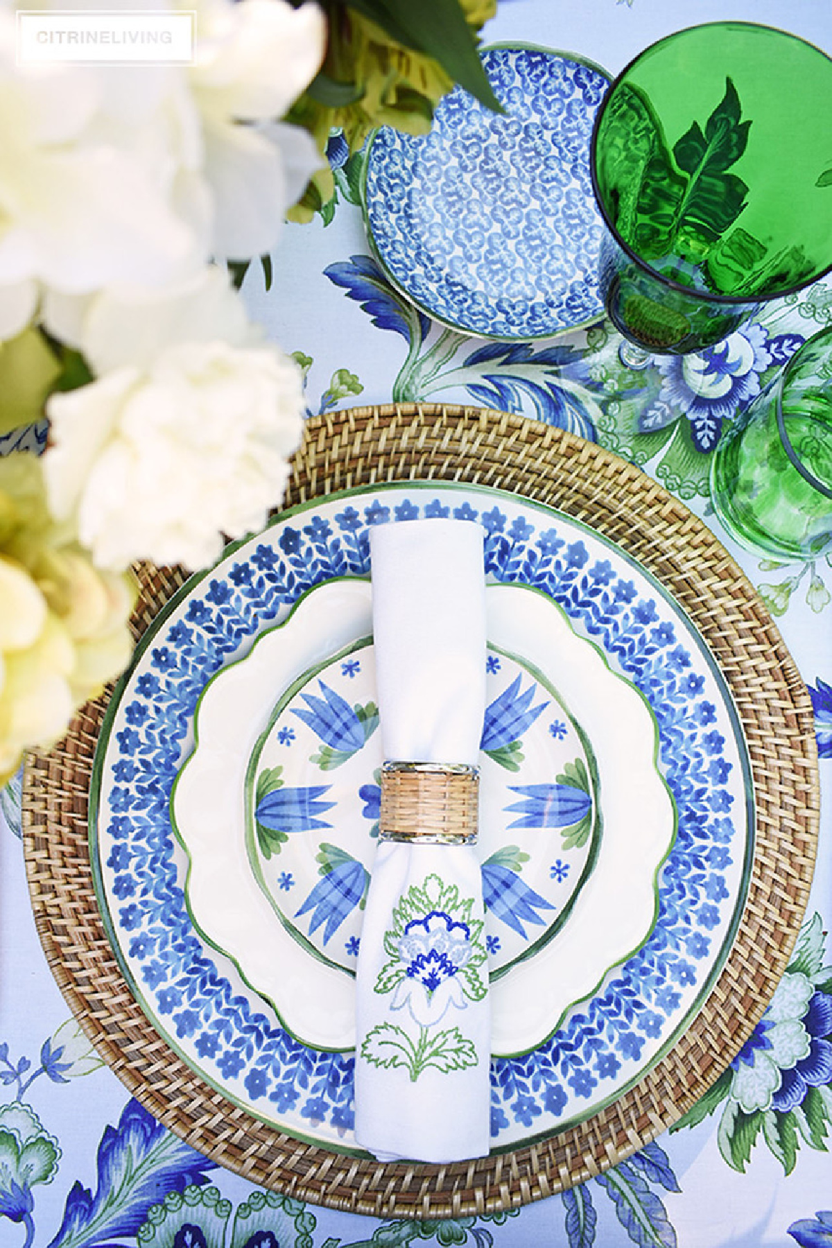 place setting with ratan charger topped with blue, white and green plates and napkin