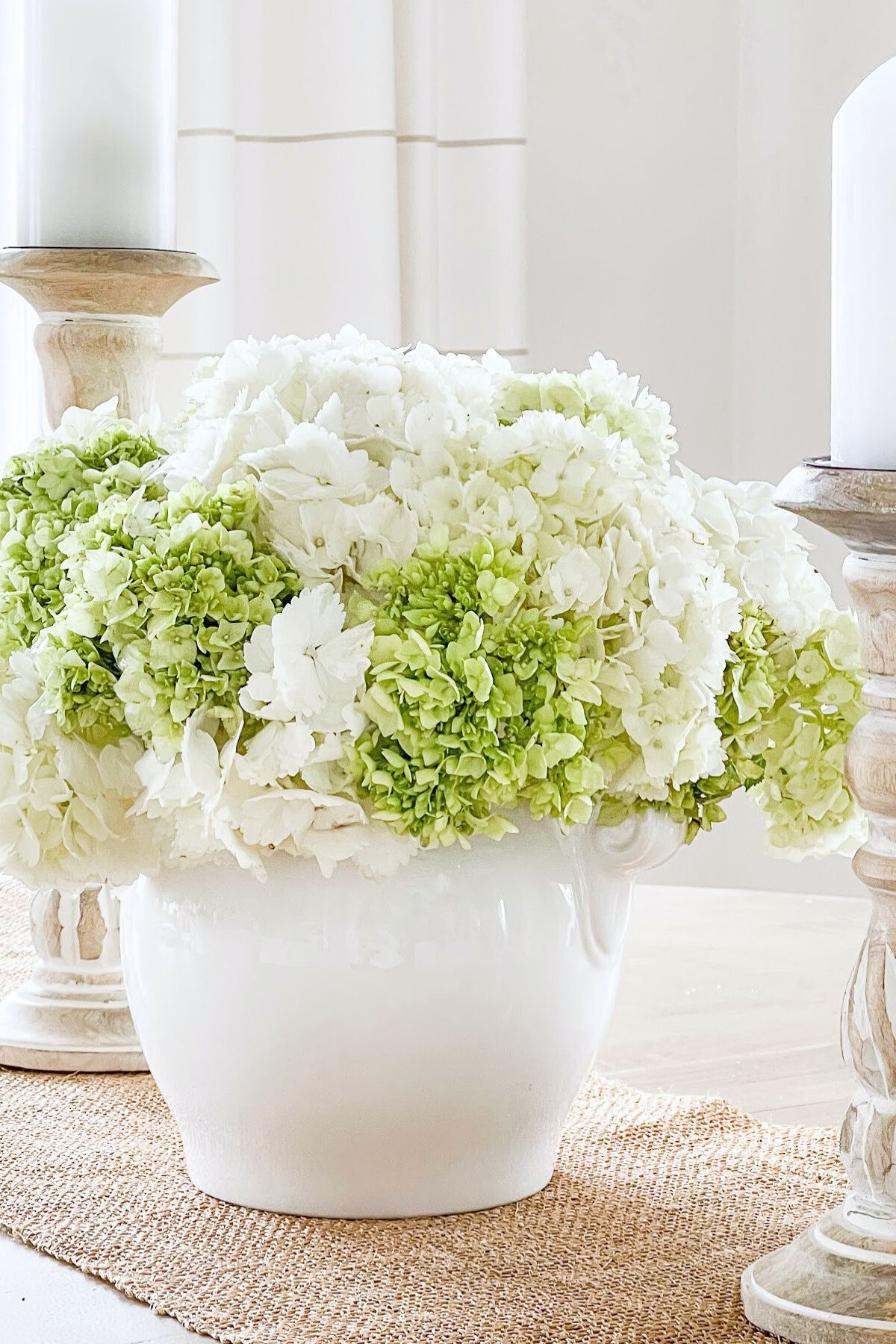 green and white hydrangeas arranged in a white pottery container