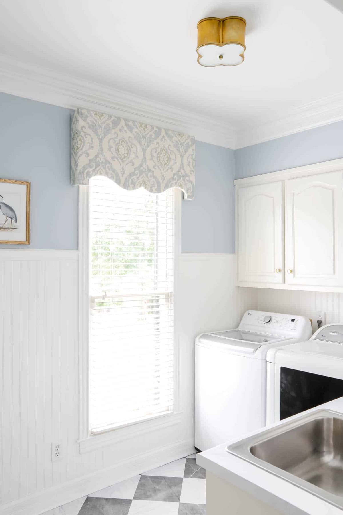 laundry room with white cabinets and medium blue walls with a matching diy window cornice