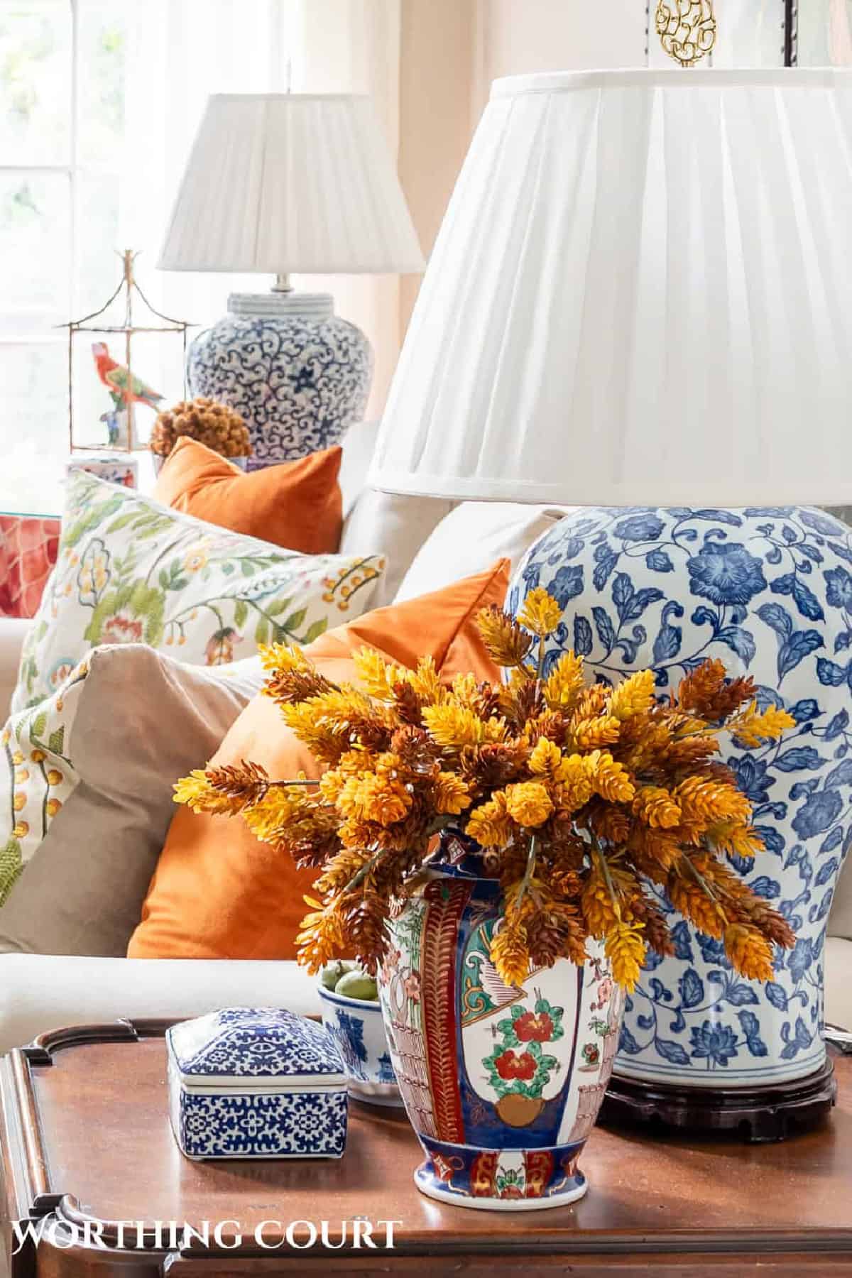 faux fall florals in a chinoiserie vase beside a blue and white lamp