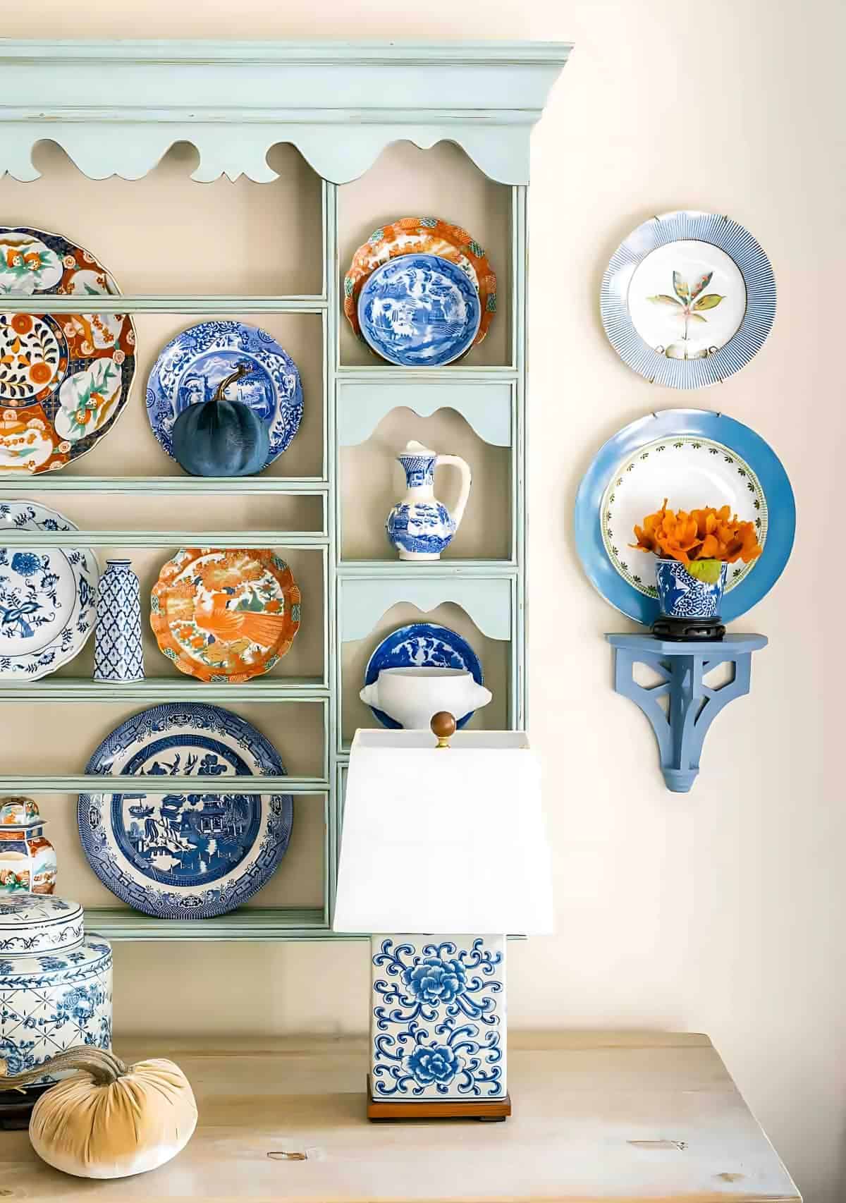 Vibrant blue and orange decorative plates displayed on a mint green vintage hutch. Elegant home decor accents for a stylish kitchen or dining room.