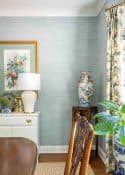 partial view of a dining room with blue grasscloth wallpaper and traditional decor