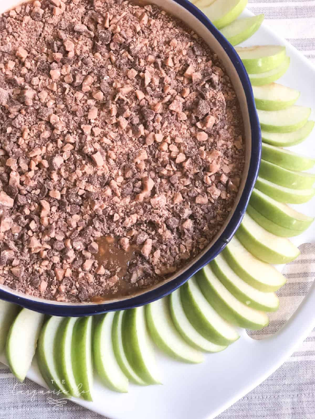 Crumbled chocolate cake with sliced green apples decoratively arranged on a white plate.