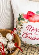 Decorative Christmas pillow with "Merry Christmas" message, holiday ornaments, and a cozy neutral background.
