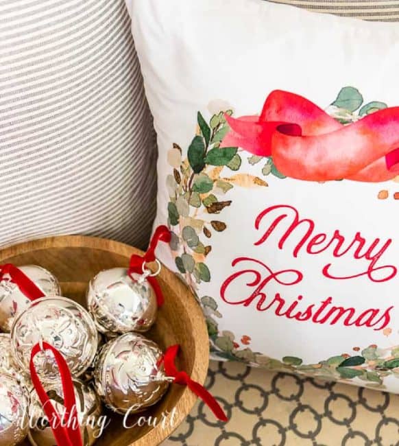 Decorative Christmas pillow with "Merry Christmas" message, holiday ornaments, and a cozy neutral background.