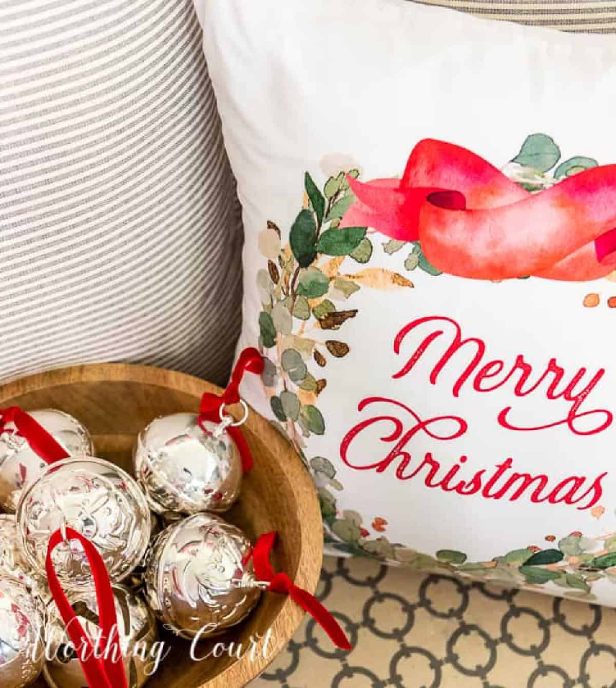 Decorative Christmas pillow with "Merry Christmas" message, holiday ornaments, and a cozy neutral background.