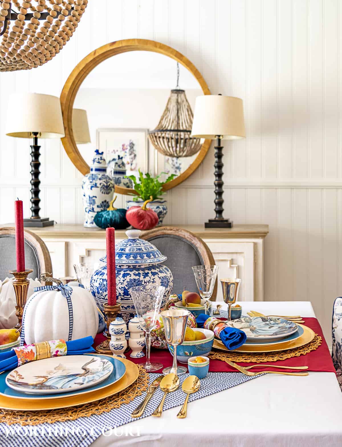 Colorful farmhouse dining table with elegant tableware and pumpkins for fall decor.