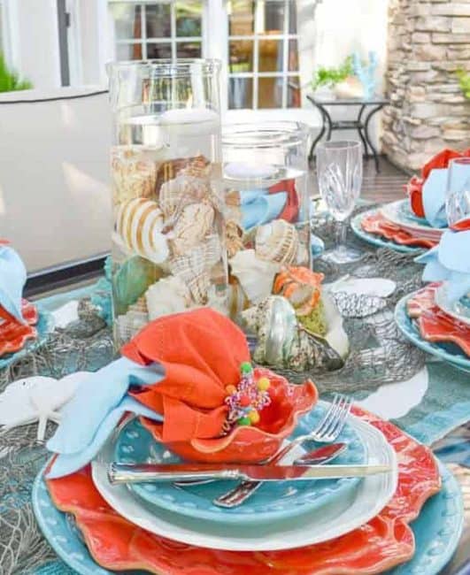 outdoor table setting with a coastal theme using turquoise and orange dishes