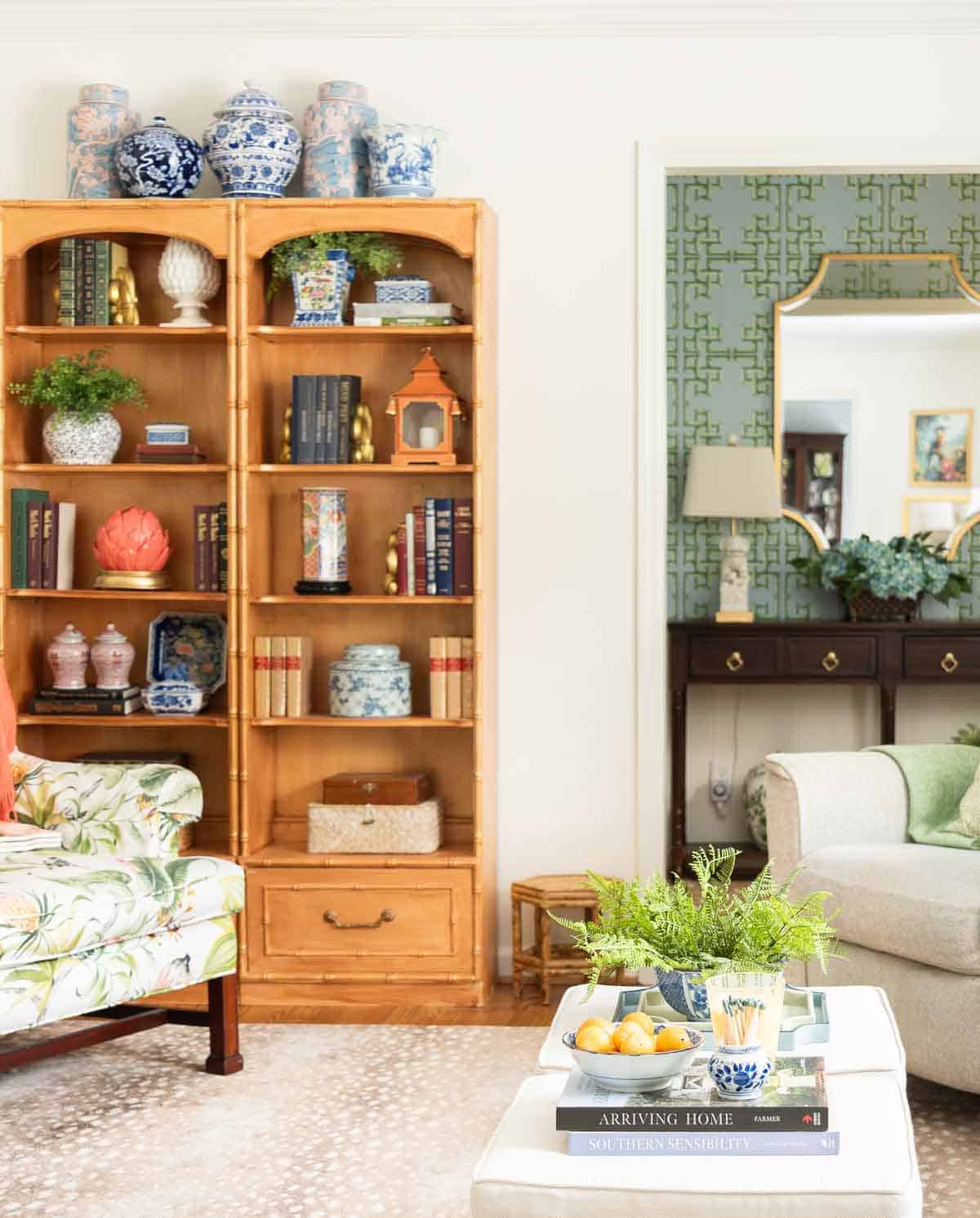 views of a small foyer decorated with chinoiserie accessories, a wood console table, and with blue and green lattice patterned wallpaper