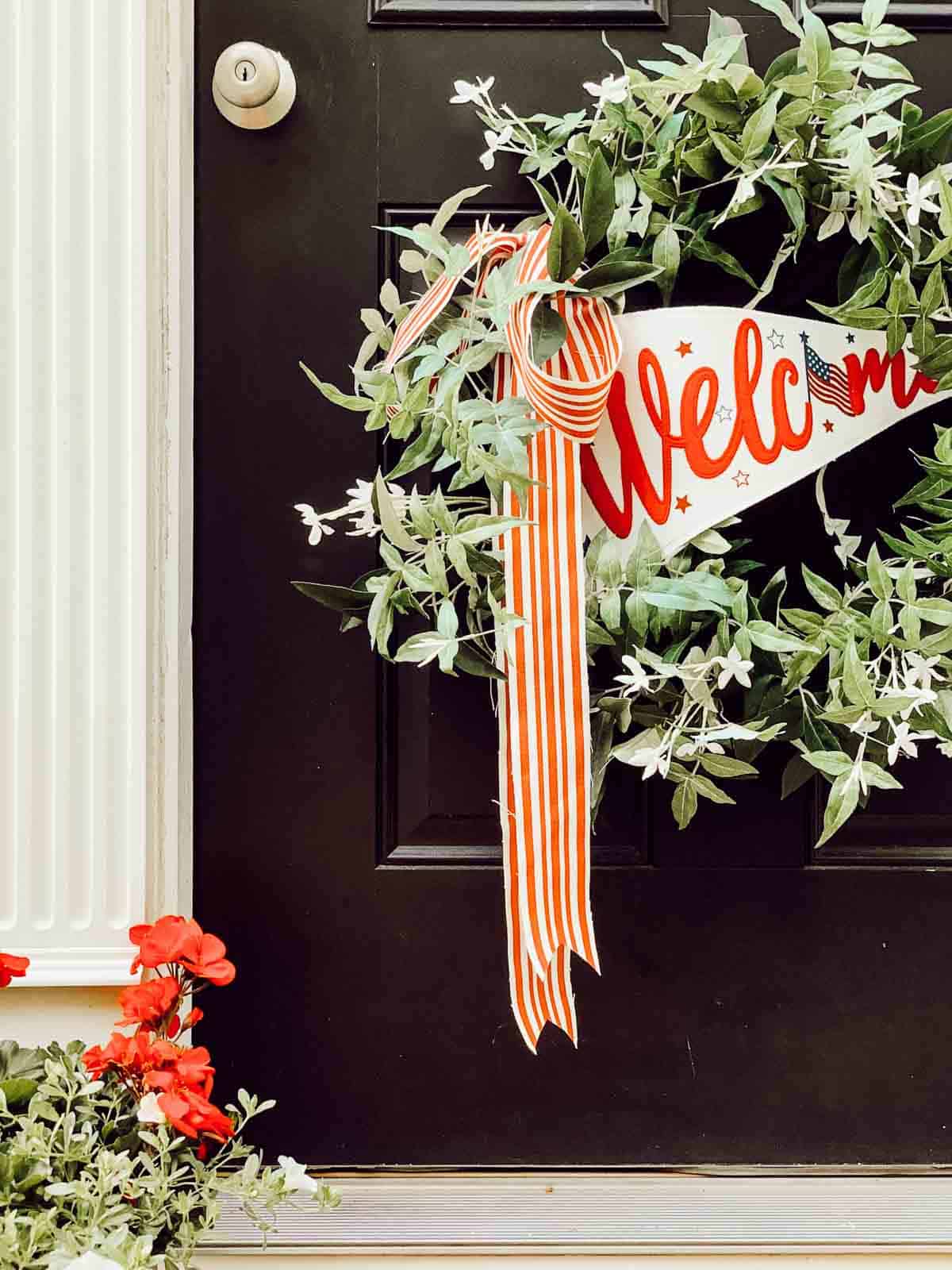 Green wreath with a welcome banner on a black front door