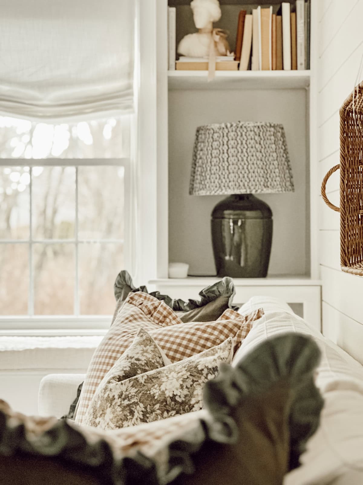 lamp on a bookcase shelf beside a couch with throw pillows