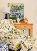 patterned armchair in front of a pine console table with colorful artwork and accessories