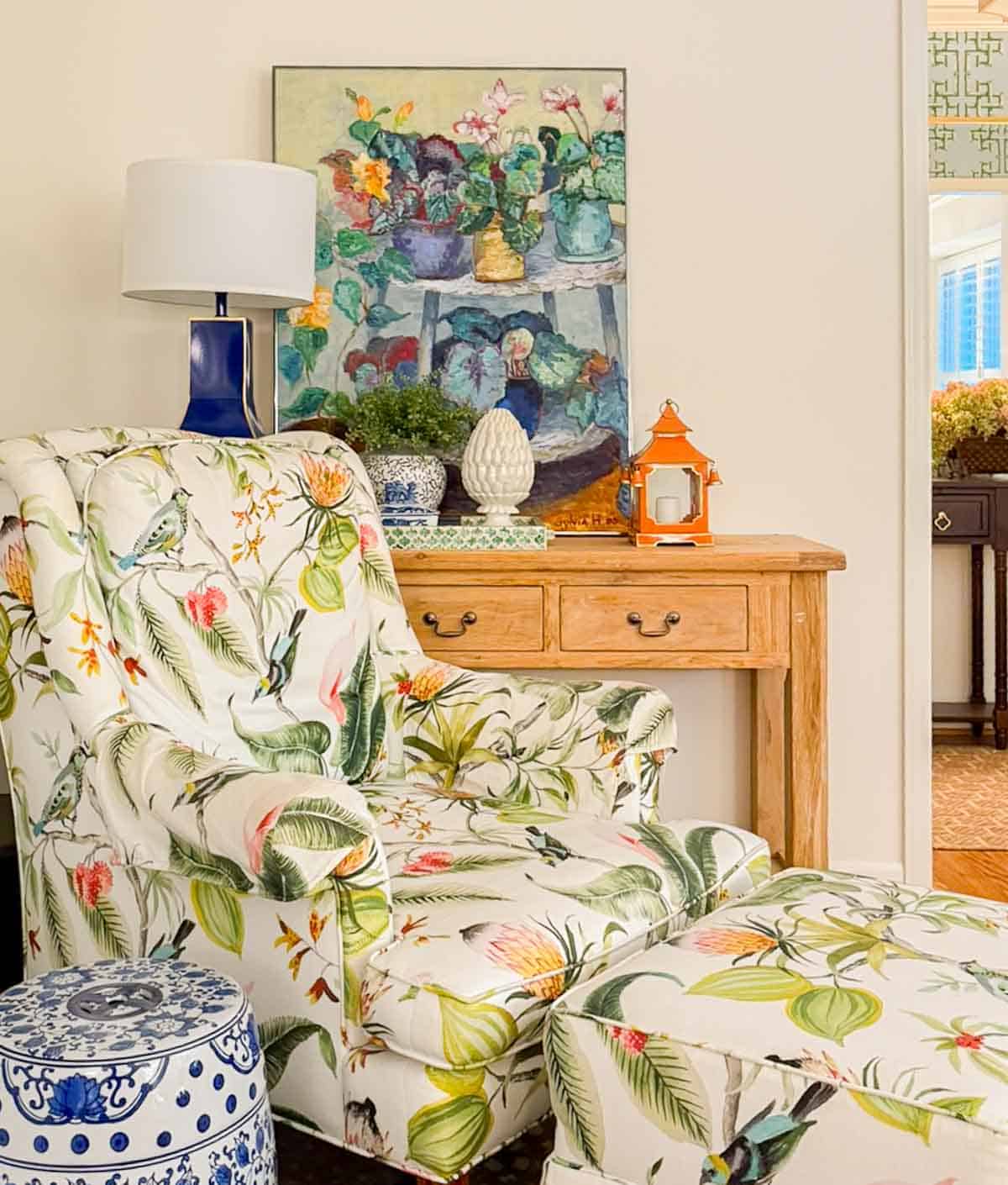 patterned armchair in front of a pine console table with colorful artwork and accessories