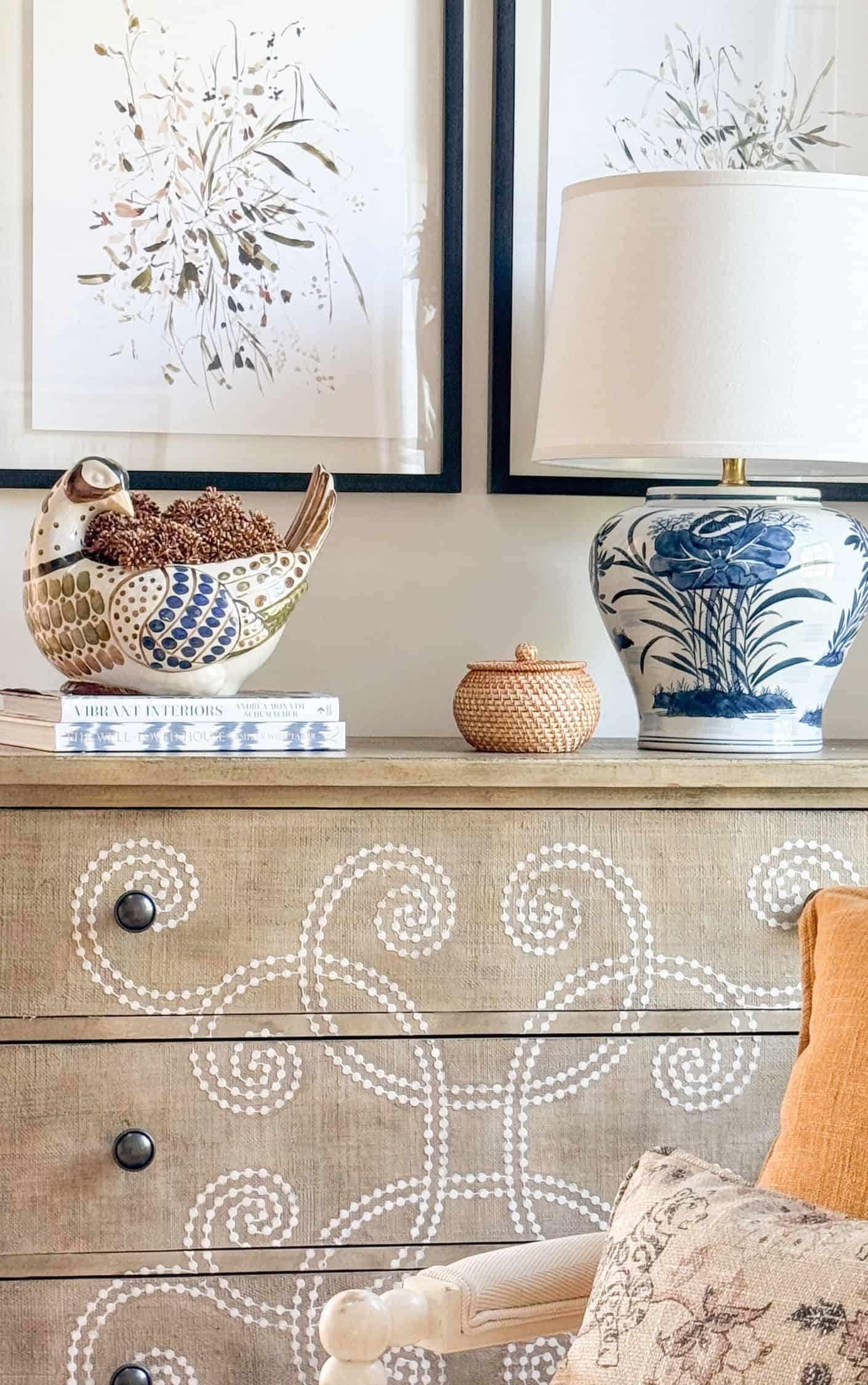 blue and white lamp along with a fanciful quail planter and books on top of a curlicue accent chest