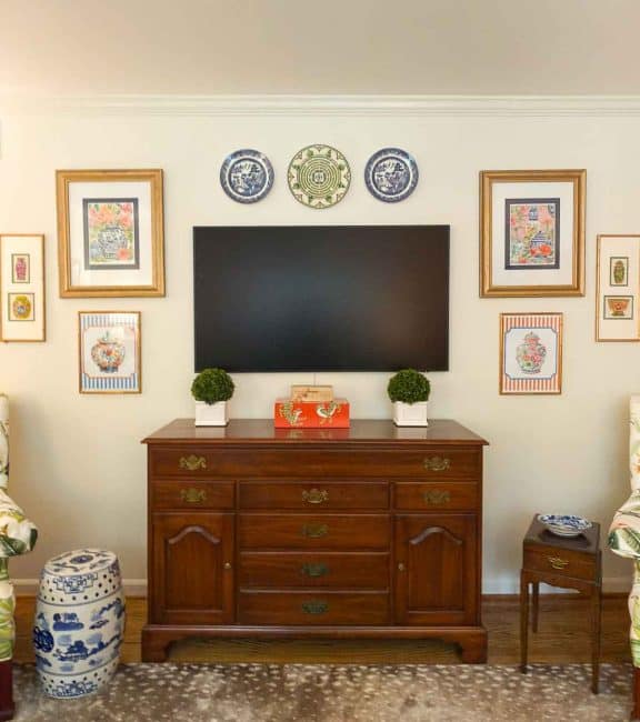 tv on wall surrounded with artwork and plates