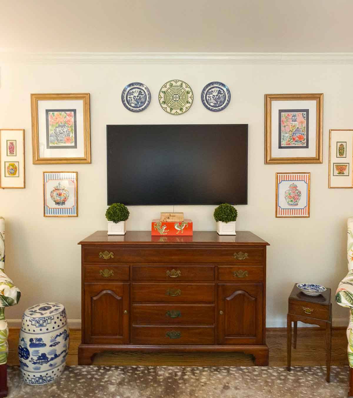 tv on wall surrounded with artwork and plates