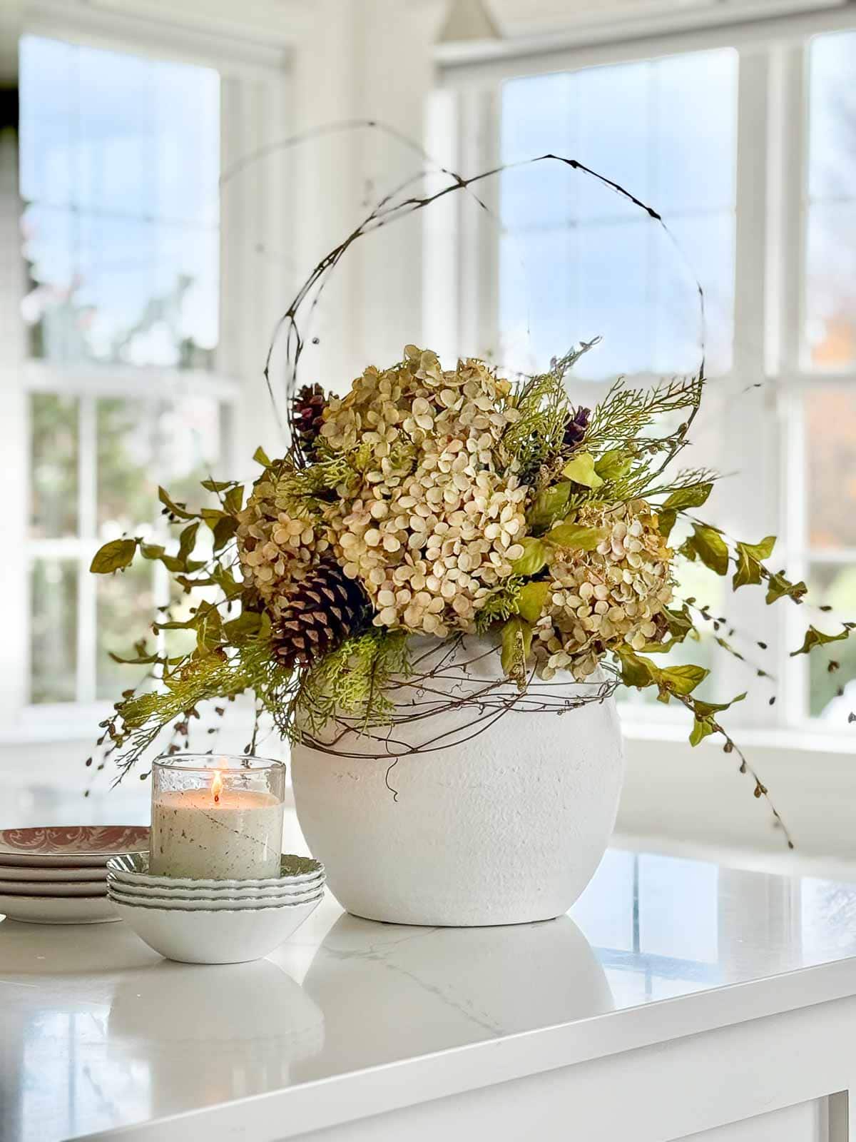white container filled with dried hydrangeas, twigs and faux greenery