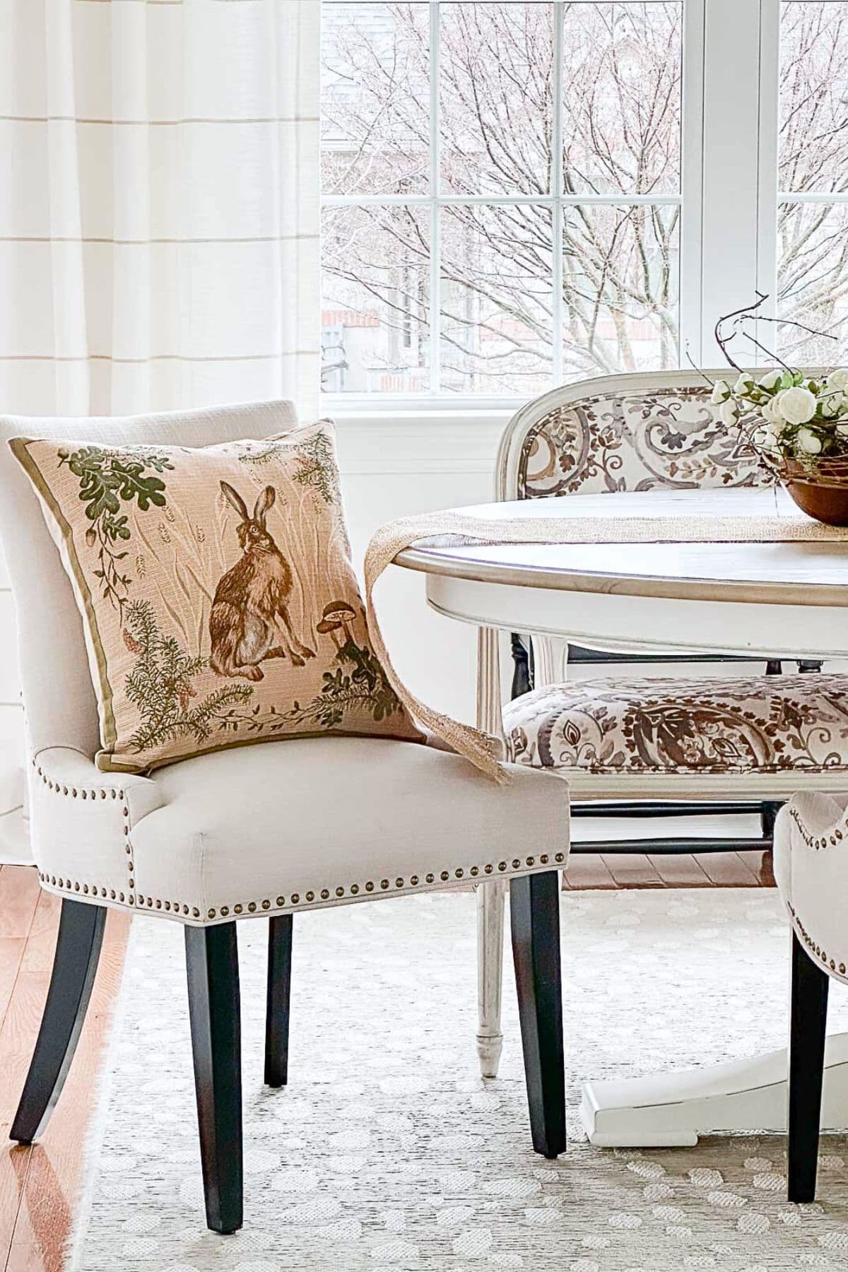 bunny throw pillow in an upholstered dining chair beside a table