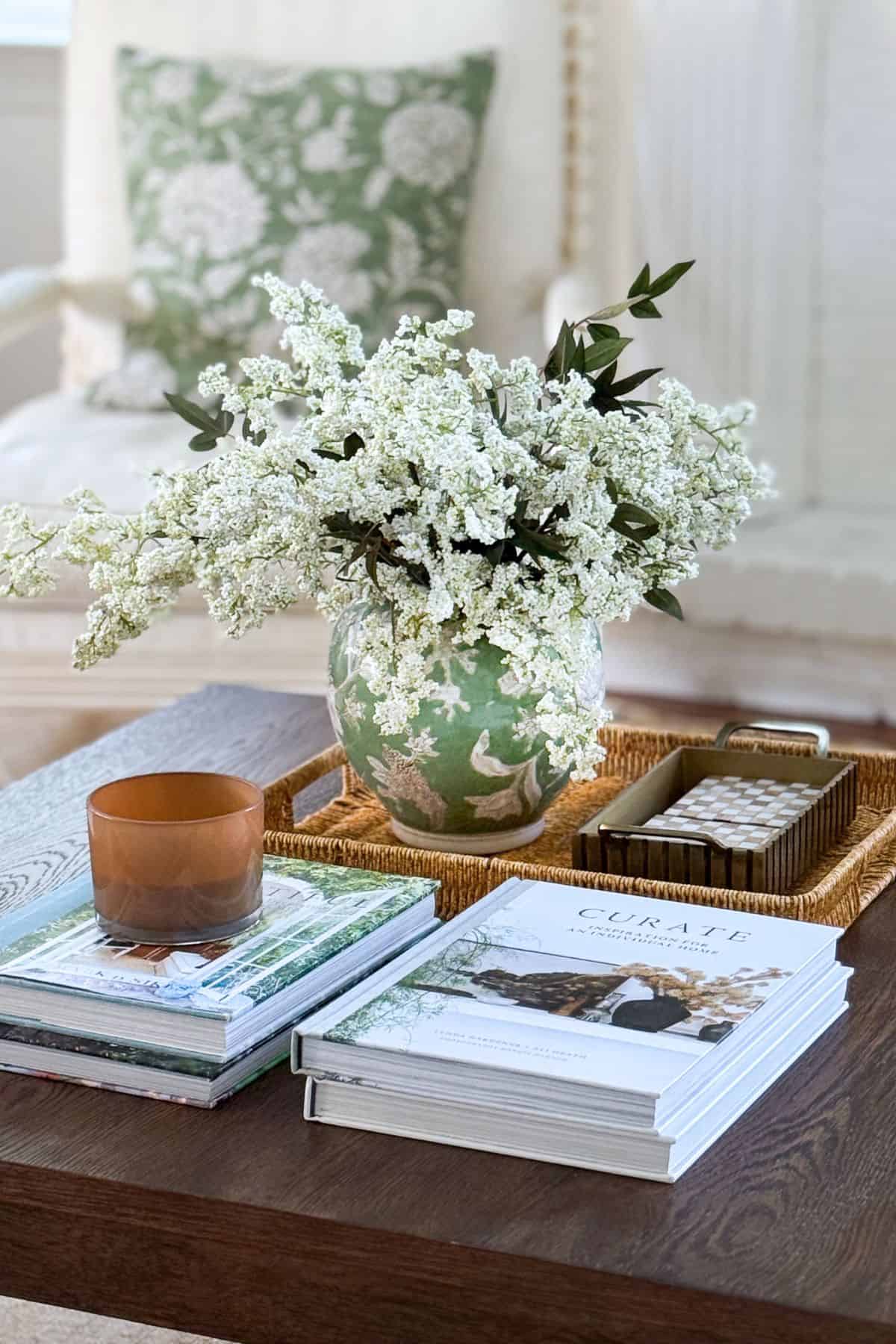 coffee table vignette featuring an arrangement of white flowers in a green and white vase