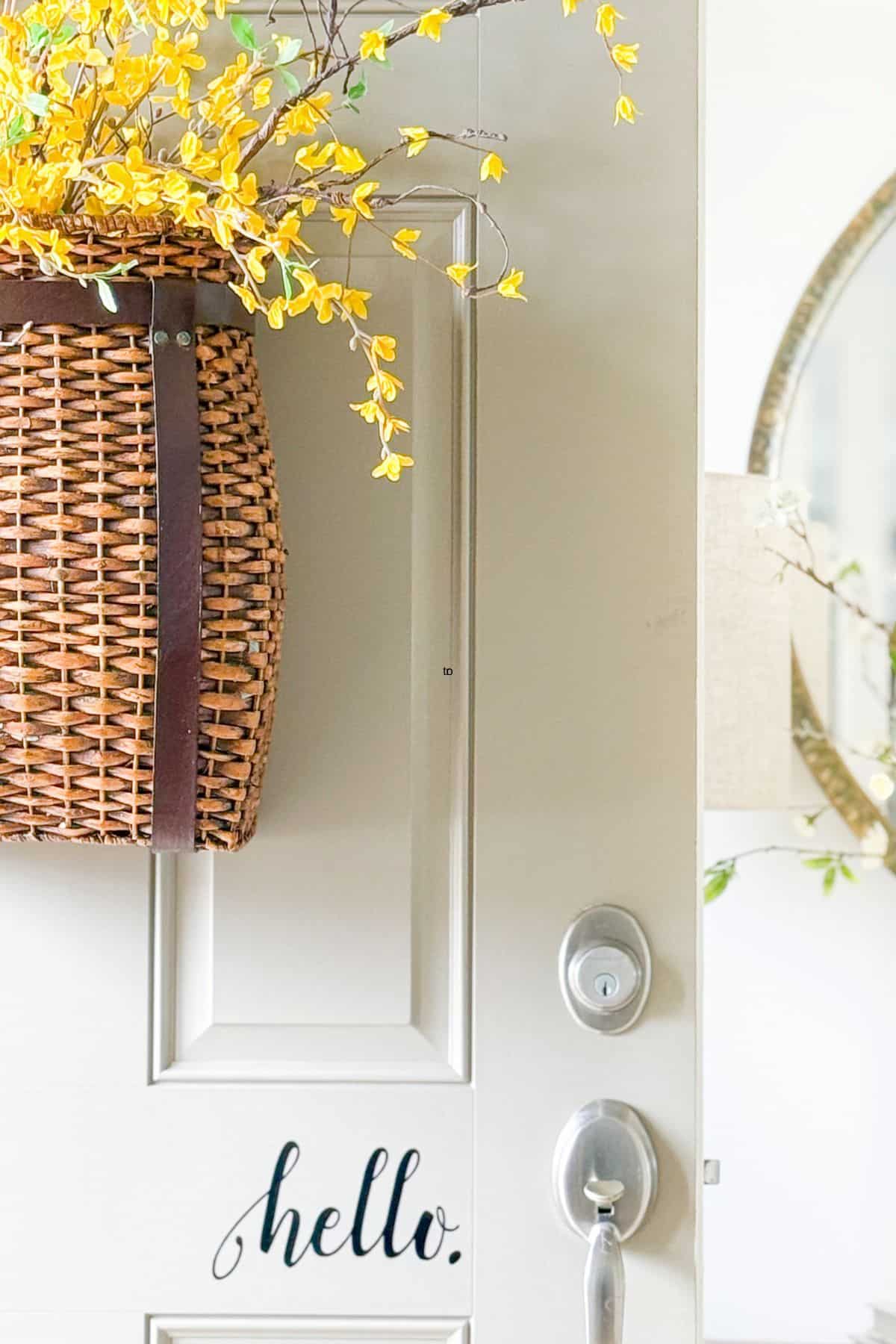 partial view of a wicker hanging basket filled with forsythia stems on a front door