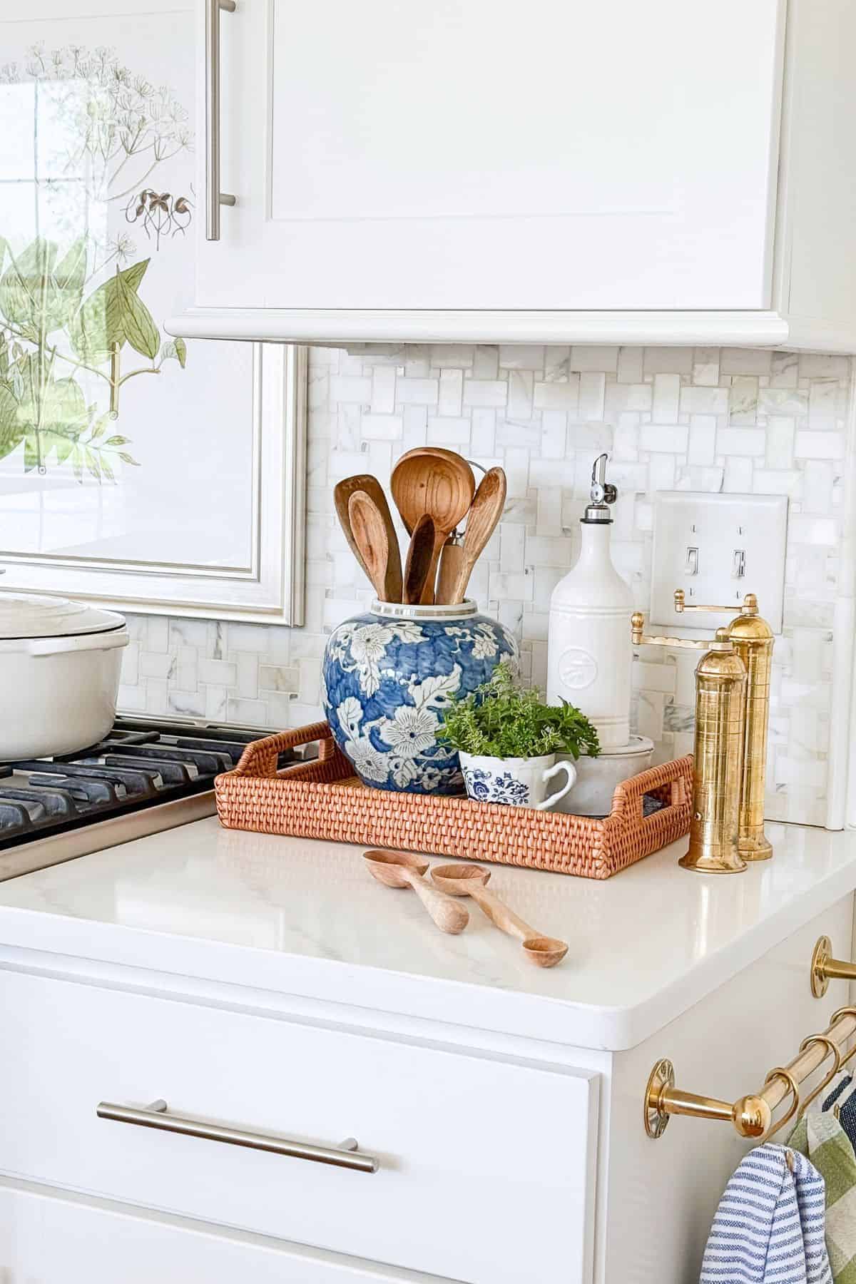 kitchen counter vignette in a woven tray with blue and white accessories and brass salt and pepper mills
