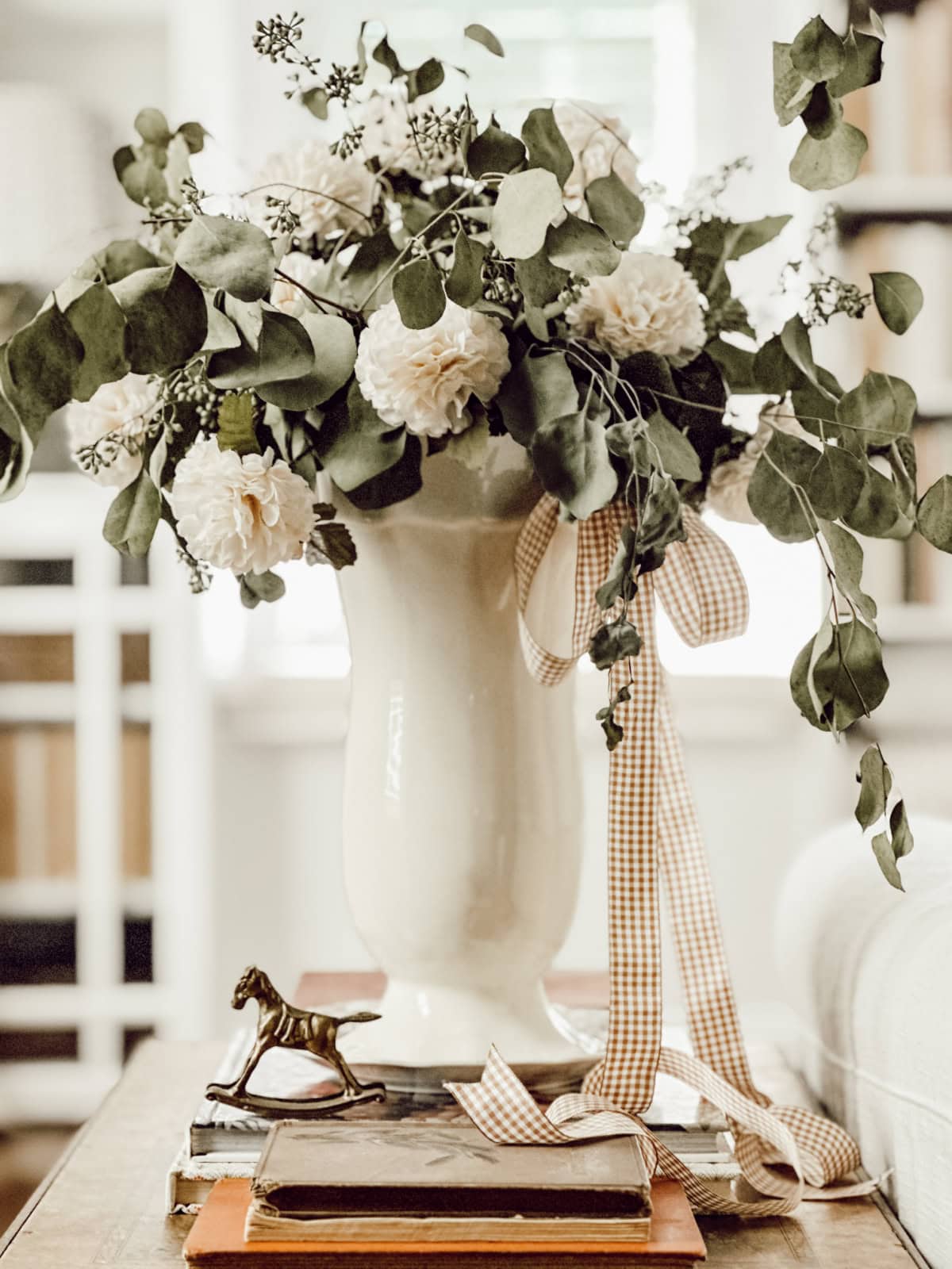 white ceramic vase filled with white flowers and greenery