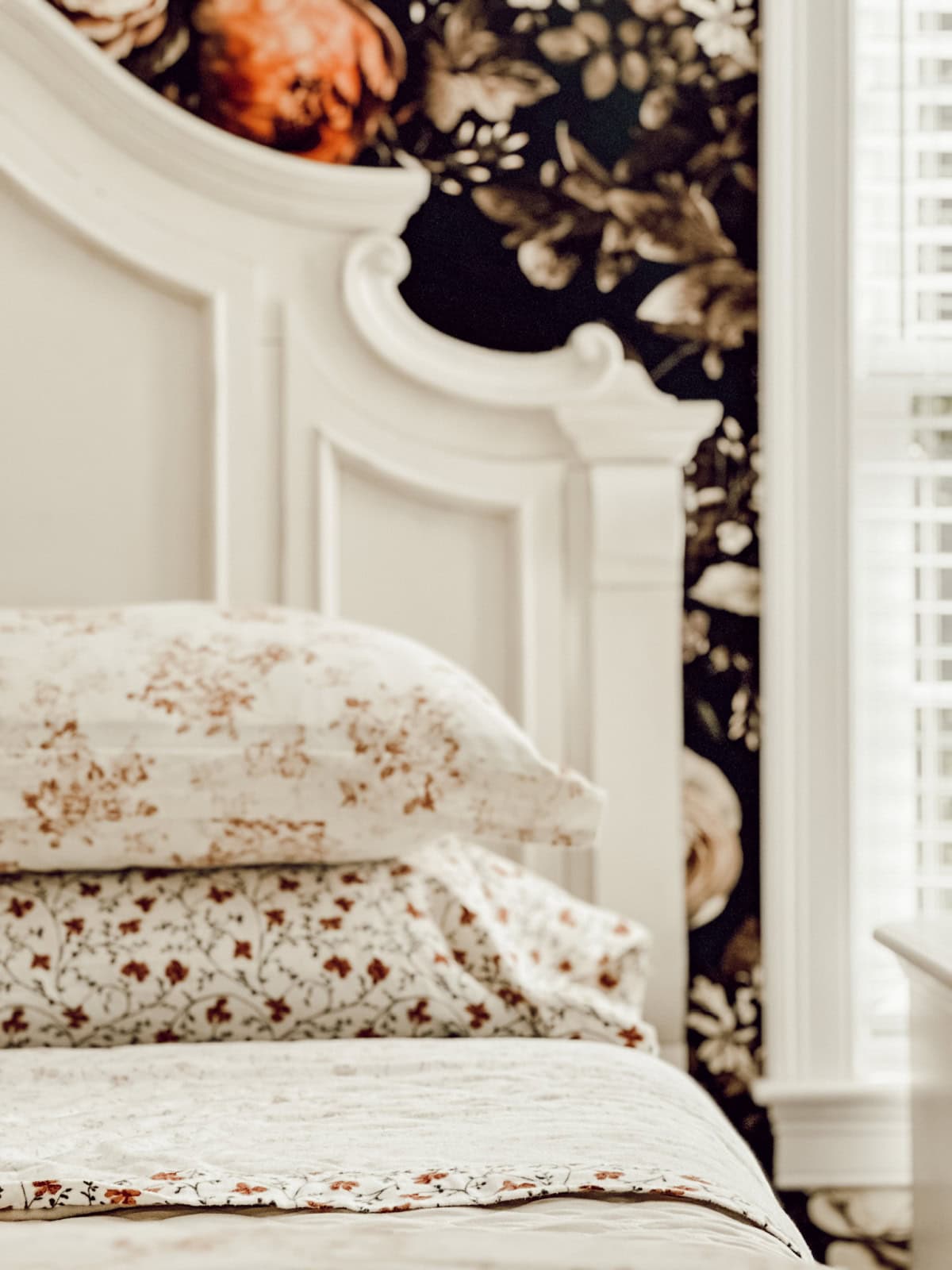 stack of bed pillows with patterned pillow cases stacked in front of a white wood headboard
