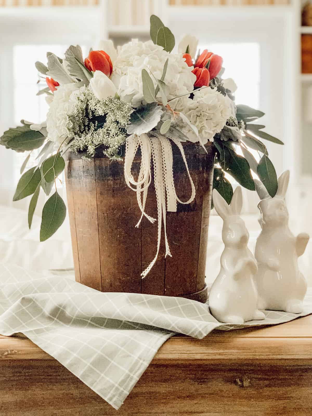 antique wood container holding a pink and white flower arrangement
