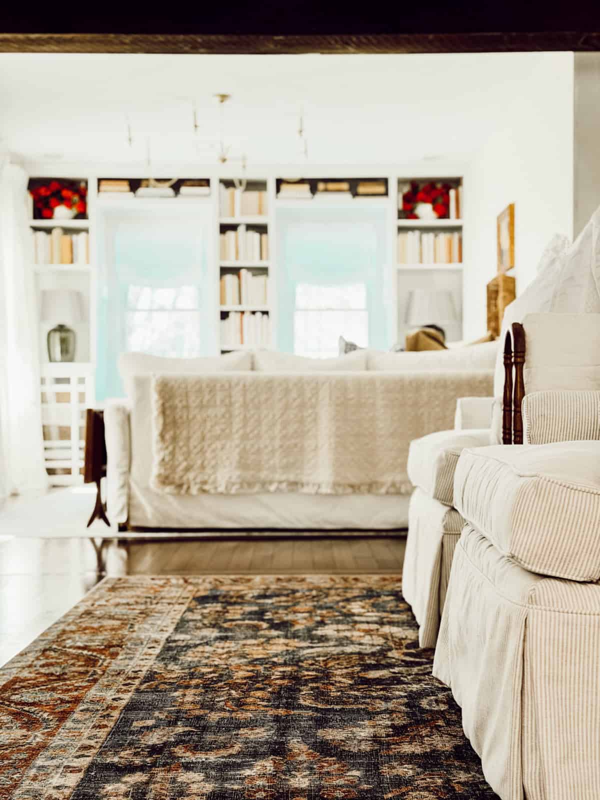 view into a living room with all white furniture and bookcases