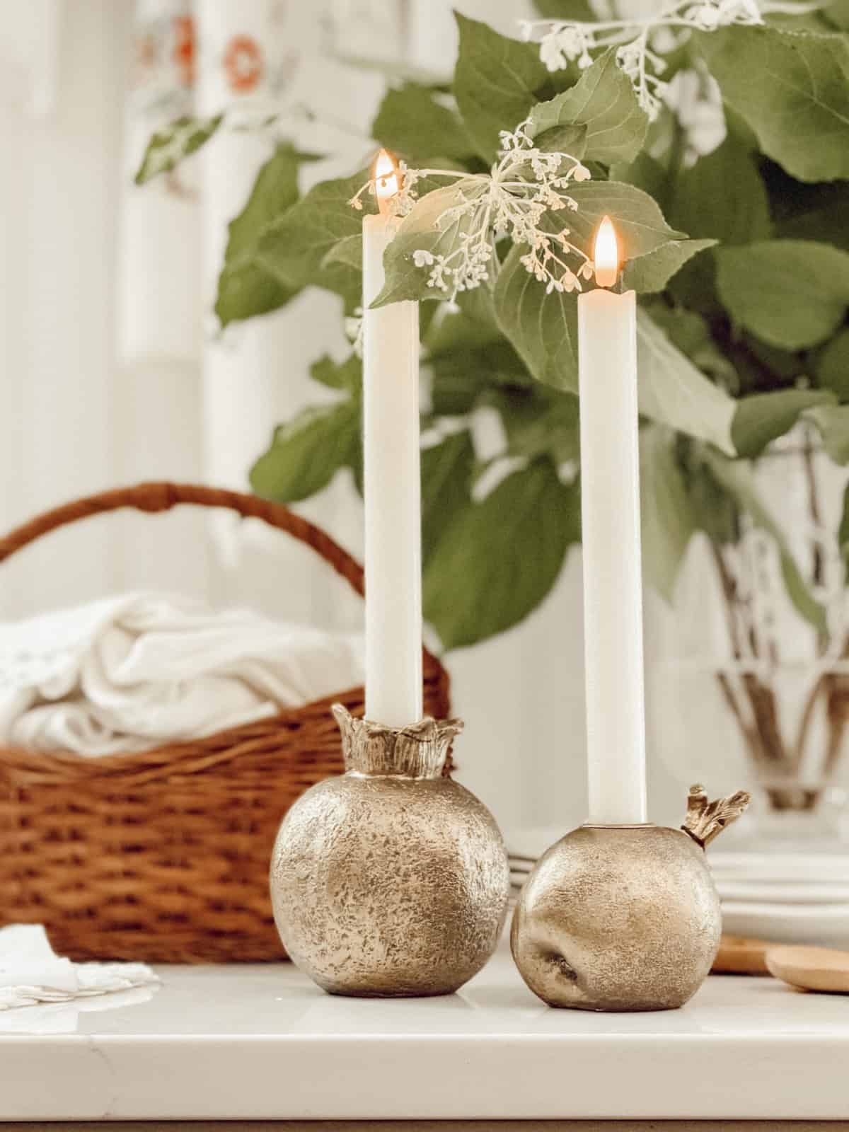 vignette featuring a pair of white candles in silver faux vegetable candle holders