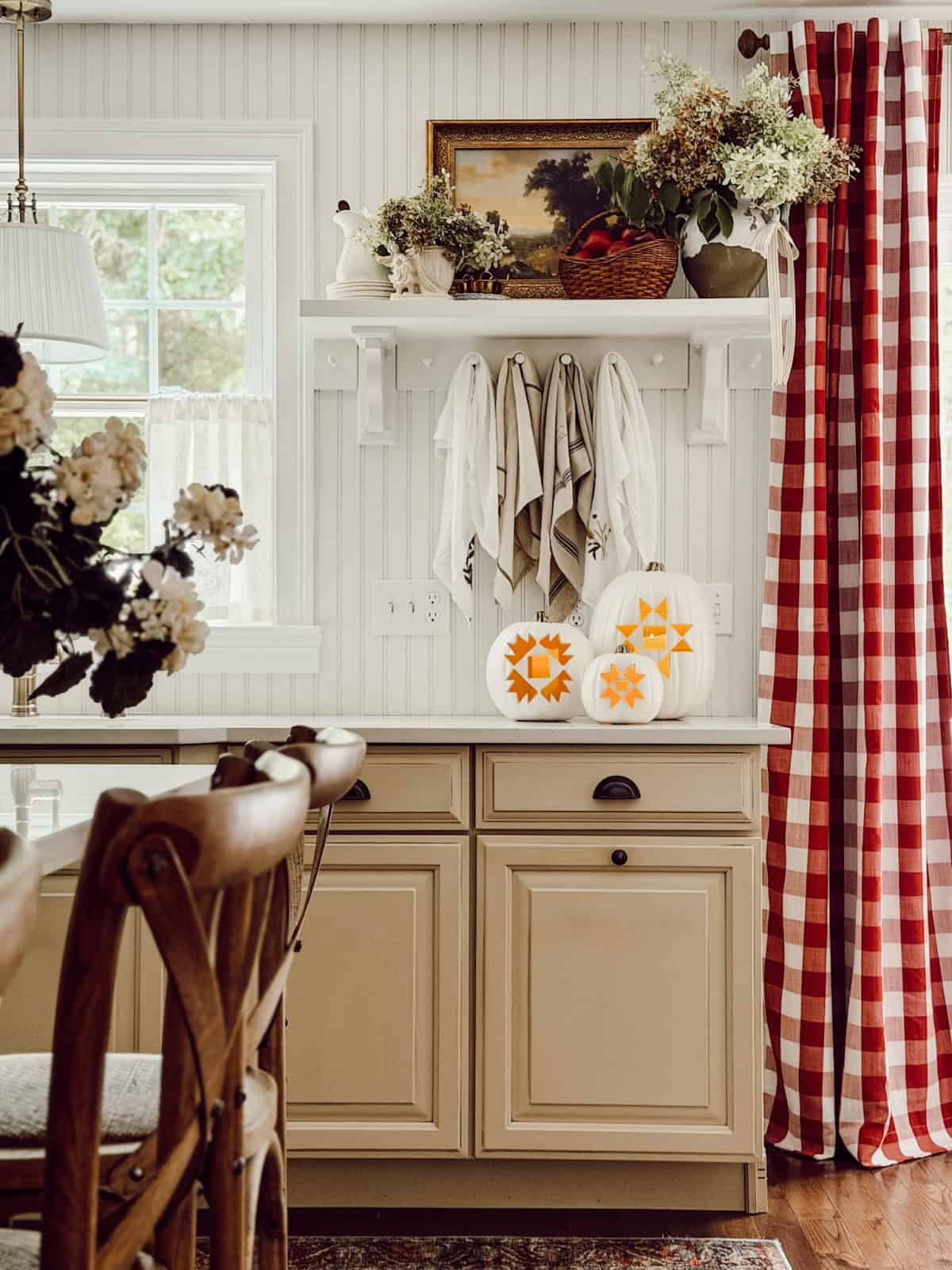 an all neutral farmhouse kitchen with red and white checked draperies