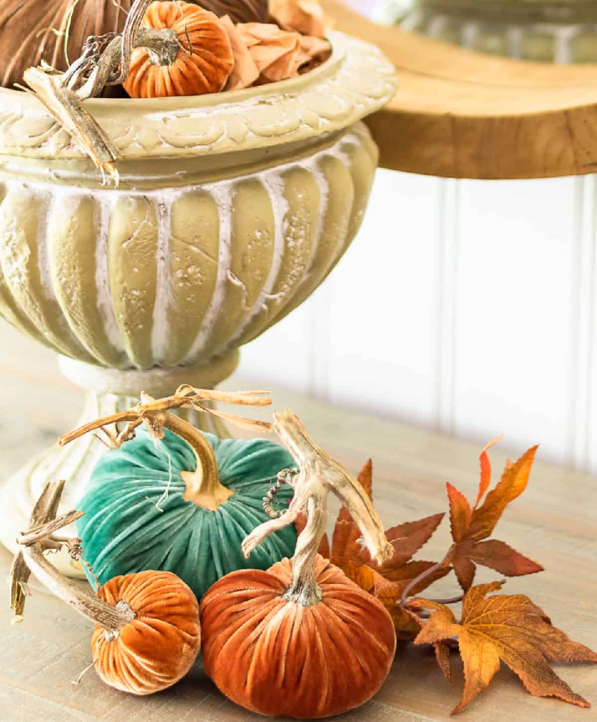 multi colored velvet pumpkins in an urn on a sideboard