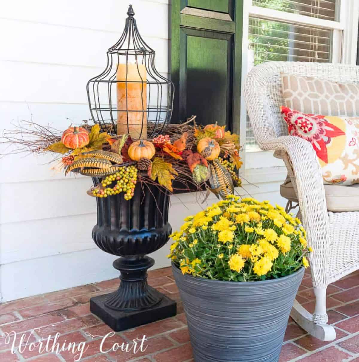 Pumpkin fall centerpiece with candles and autumn leaves on outdoor porch.