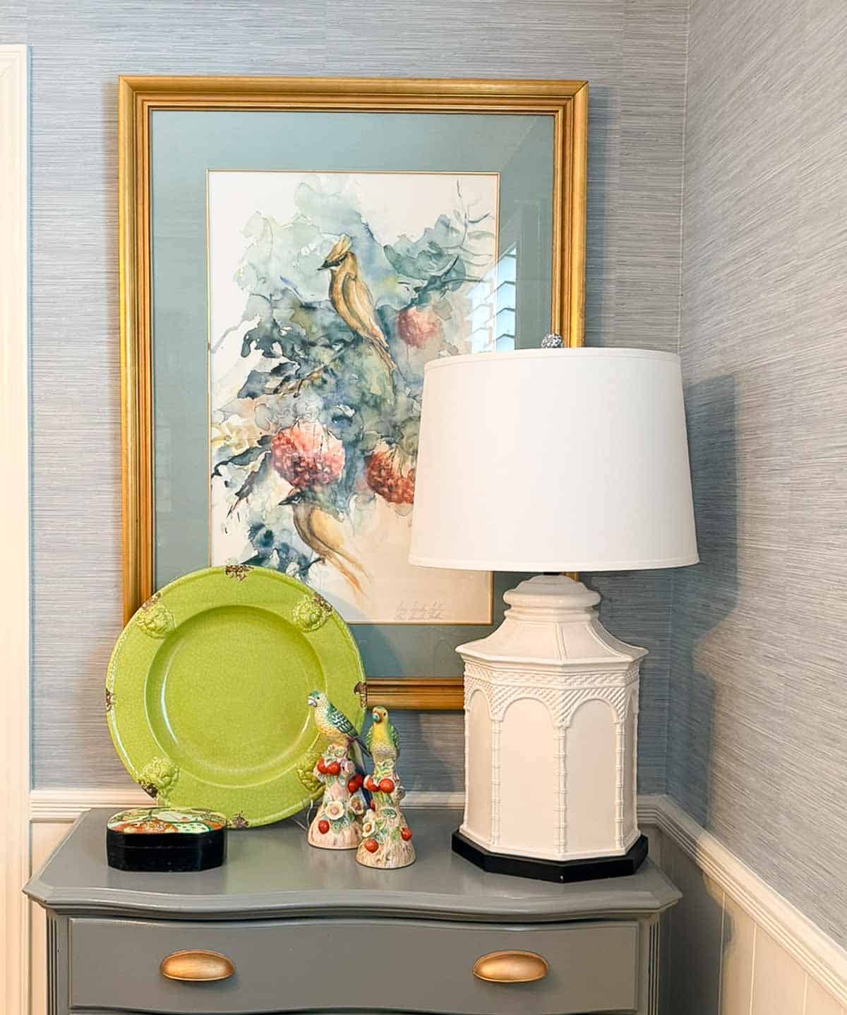 white lamp on gray chest with traditional style artwork and accessories