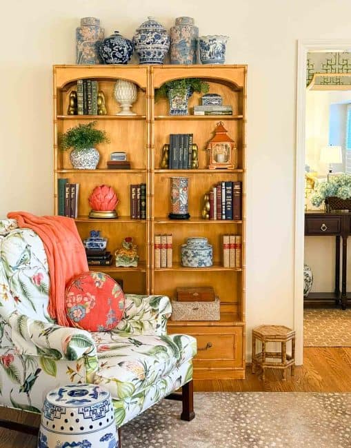 bookcases beside a colorful armchair filled with chinoiserie accessories