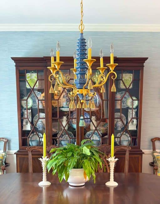 traditional china cabinet filled with chinoiserie items behind dining room table with a pagoda style chandelier