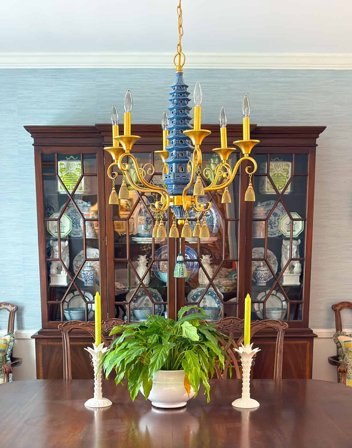traditional china cabinet filled with chinoiserie items behind dining room table with a pagoda style chandelier