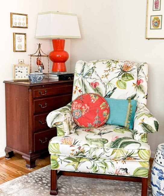wing chair covered in colorful fabric beside mahogany accent chest topped with colorful chinoiserie accessories
