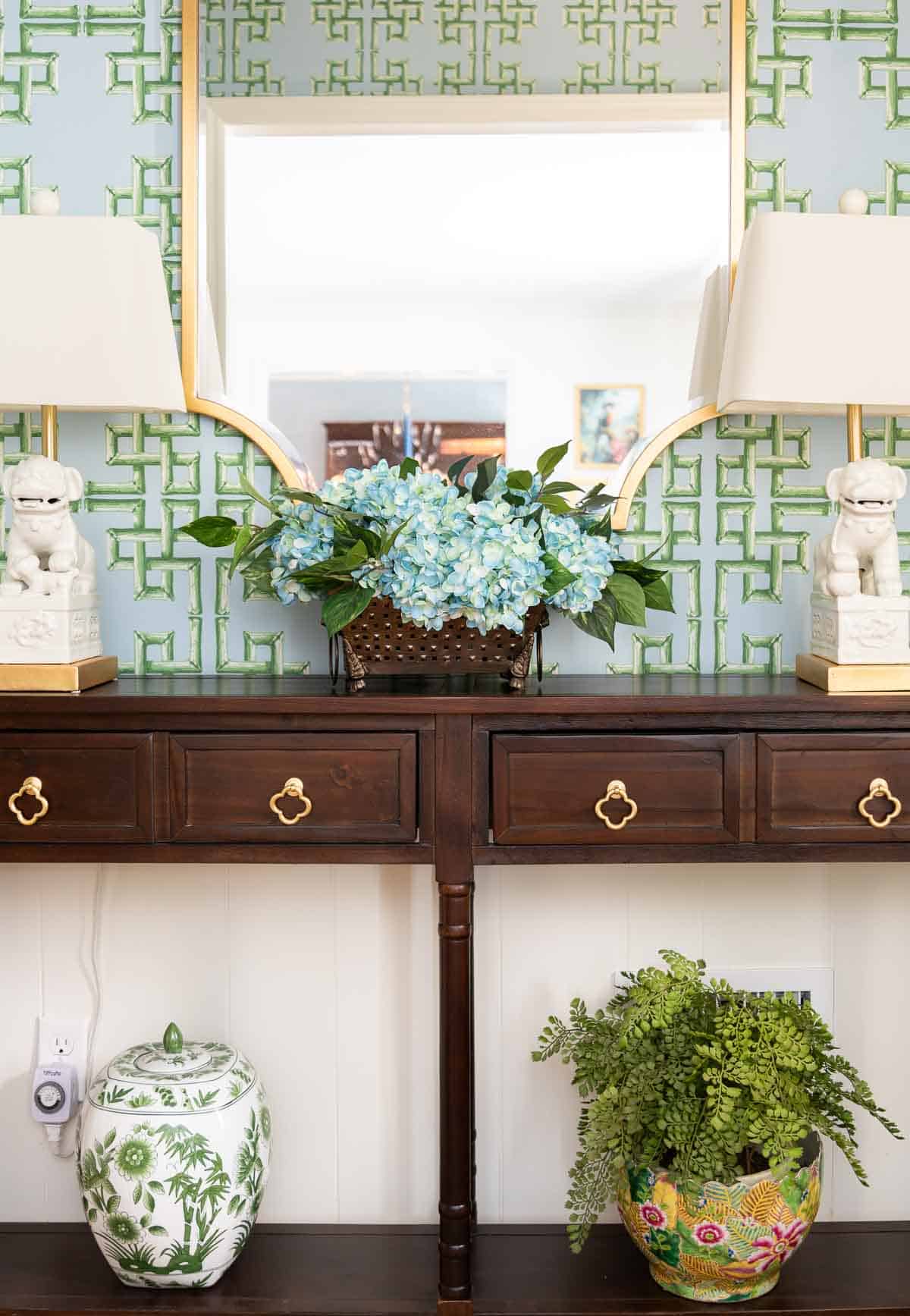 brown wood console table with hydrangea arrangement and chinoiserie accessories
