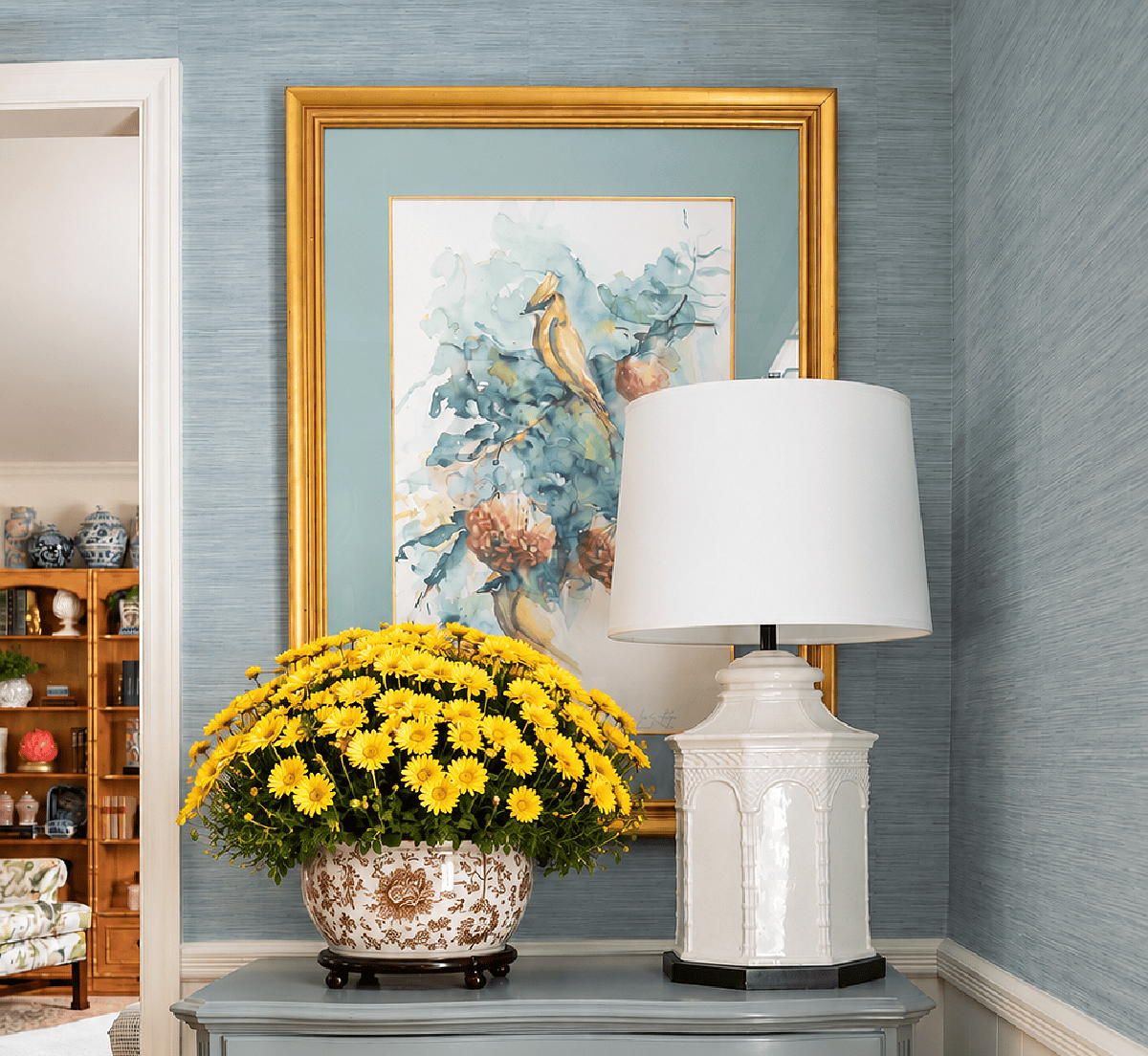 Decorative floral arrangement with framed artwork and table lamp in living room.