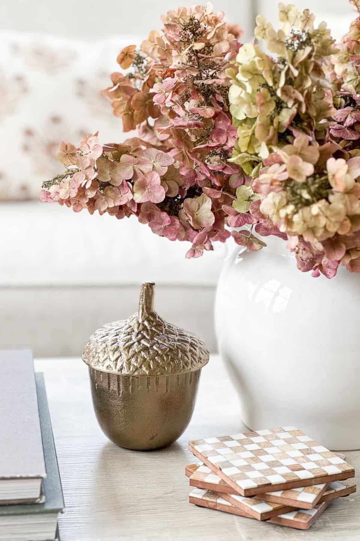 dried hydrangeas arranged in a white container beside a large acorn shaped box