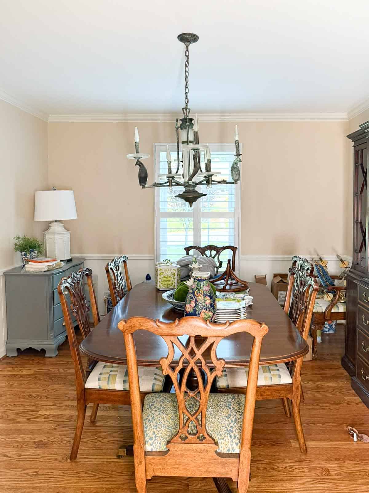 before image of a Traditional dining room with blue grasscloth walls, antique wood dining table and chairs, blue and white china, brass chandelier, and colorful chinoiserie accents.