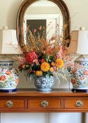 foyer console table with matching lamps on each end and a fall floral arrangement in a vase in the center